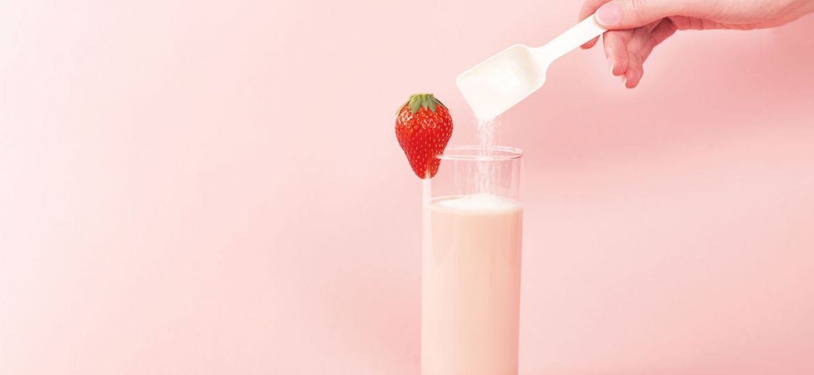 Strawberry smoothie and a spoon with collagen powder or protein.